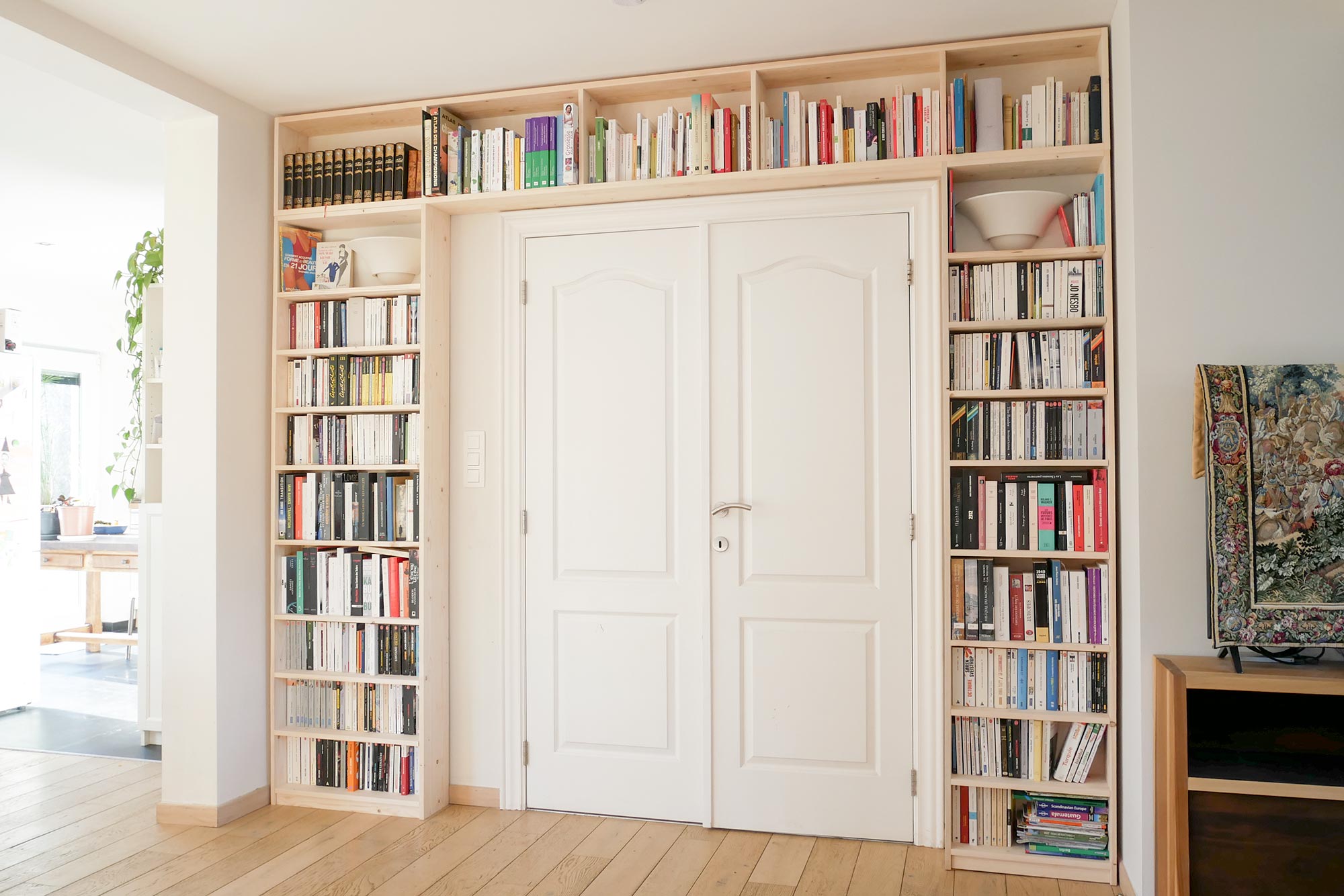 bibliothèque en sapin intégrée autour d'une double porte, avec livres